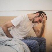 Young man in sleepwear suffering from headache in morning